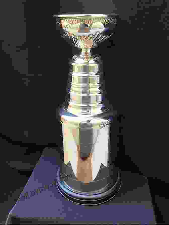 The Coveted Stanley Cup Trophy, The Ultimate Prize In Professional Ice Hockey, Stands Proudly In The Foreground, Its Silver Surface Gleaming Under The Warm Glow Of The Arena Lights. The St. Louis Blues Logo Is Prominently Displayed On The Trophy, A Testament To Their Hard Fought Journey To The Top Of The NHL. Glorious: The St Louis Blues Historic Quest For The 2024 Stanley Cup